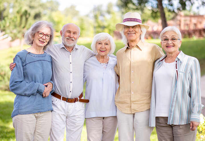 Group of Senior Friends Smiling Outdoors Near Independent Living Facility Group of Senior Friends Smiling Outdoors Near Independent Living Facility