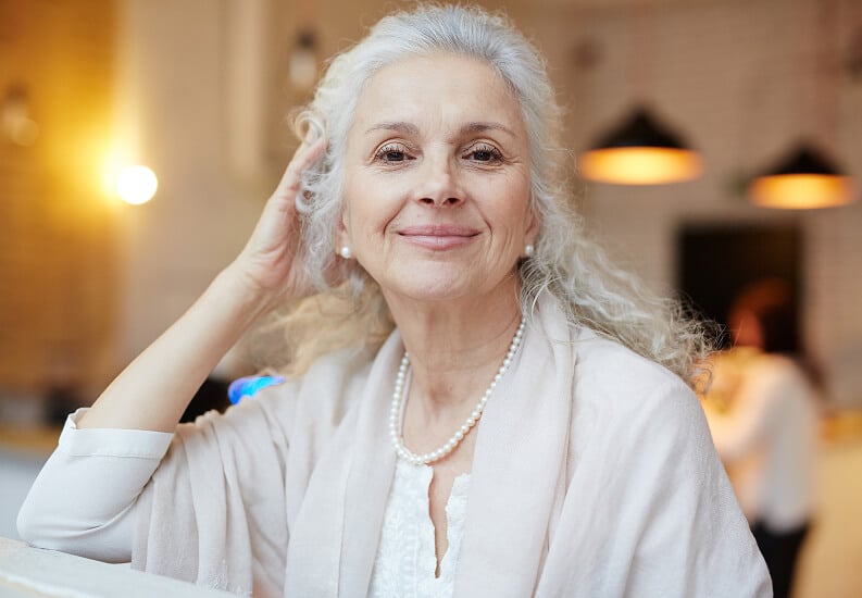 Smiling Elderly Woman Sitting Inside Independent Living Facility Smiling Elderly Woman Sitting Inside Independent Living Facility