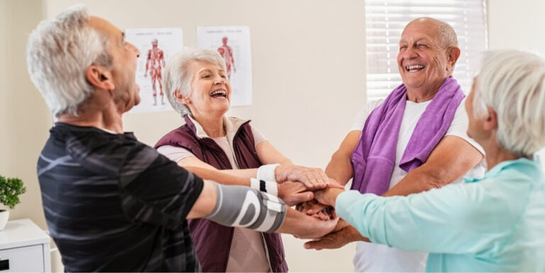 Elderly Group Stacking Hands during Therapy Session at Assisted Living Facility